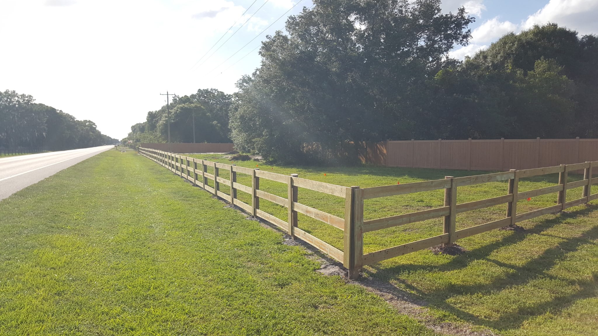 Three-board wood rail fence along a Florida road built by Wilson's Fencing