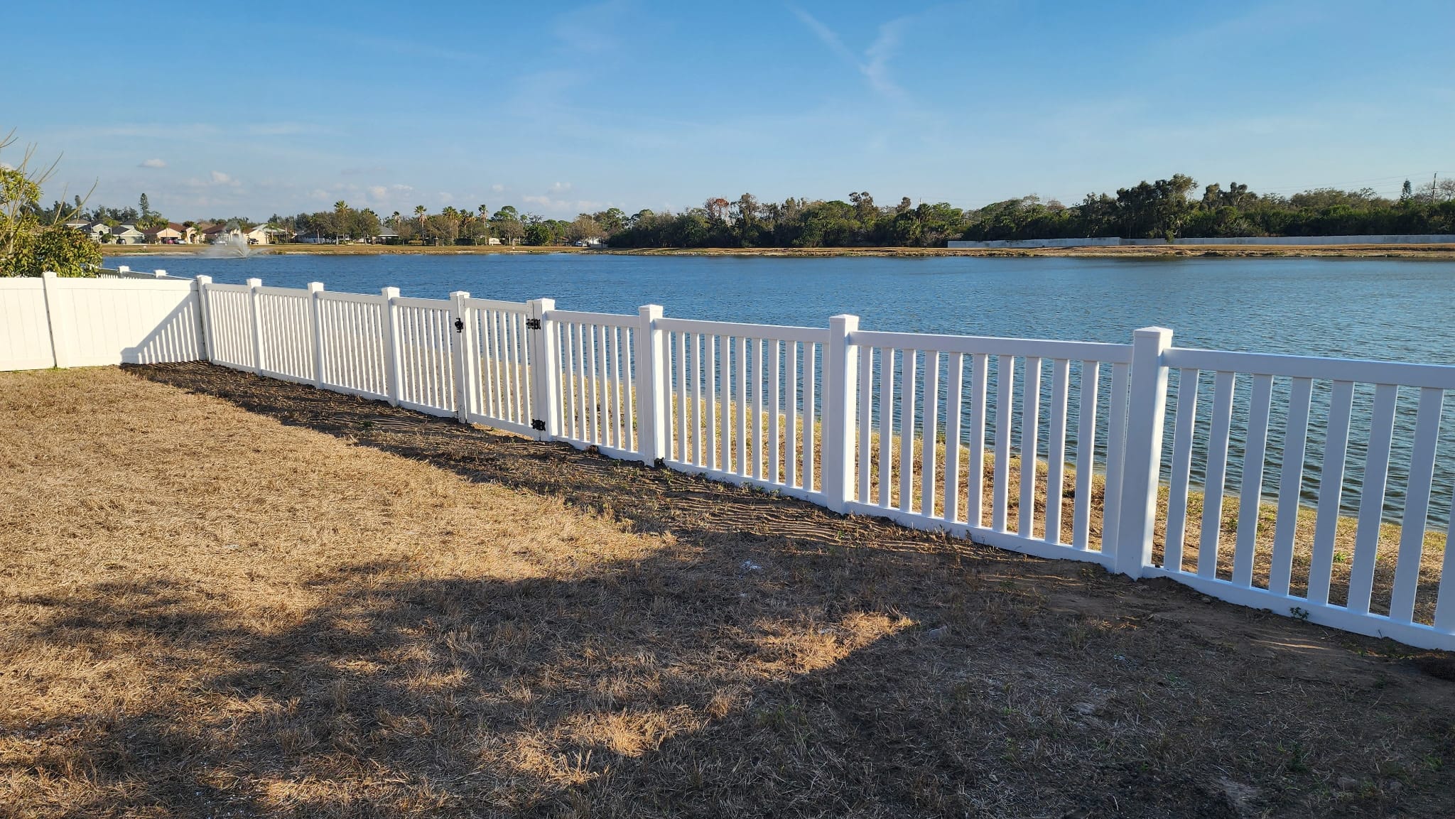 White vinyl picket fence by a Florida lake built by Wilson's Fencing