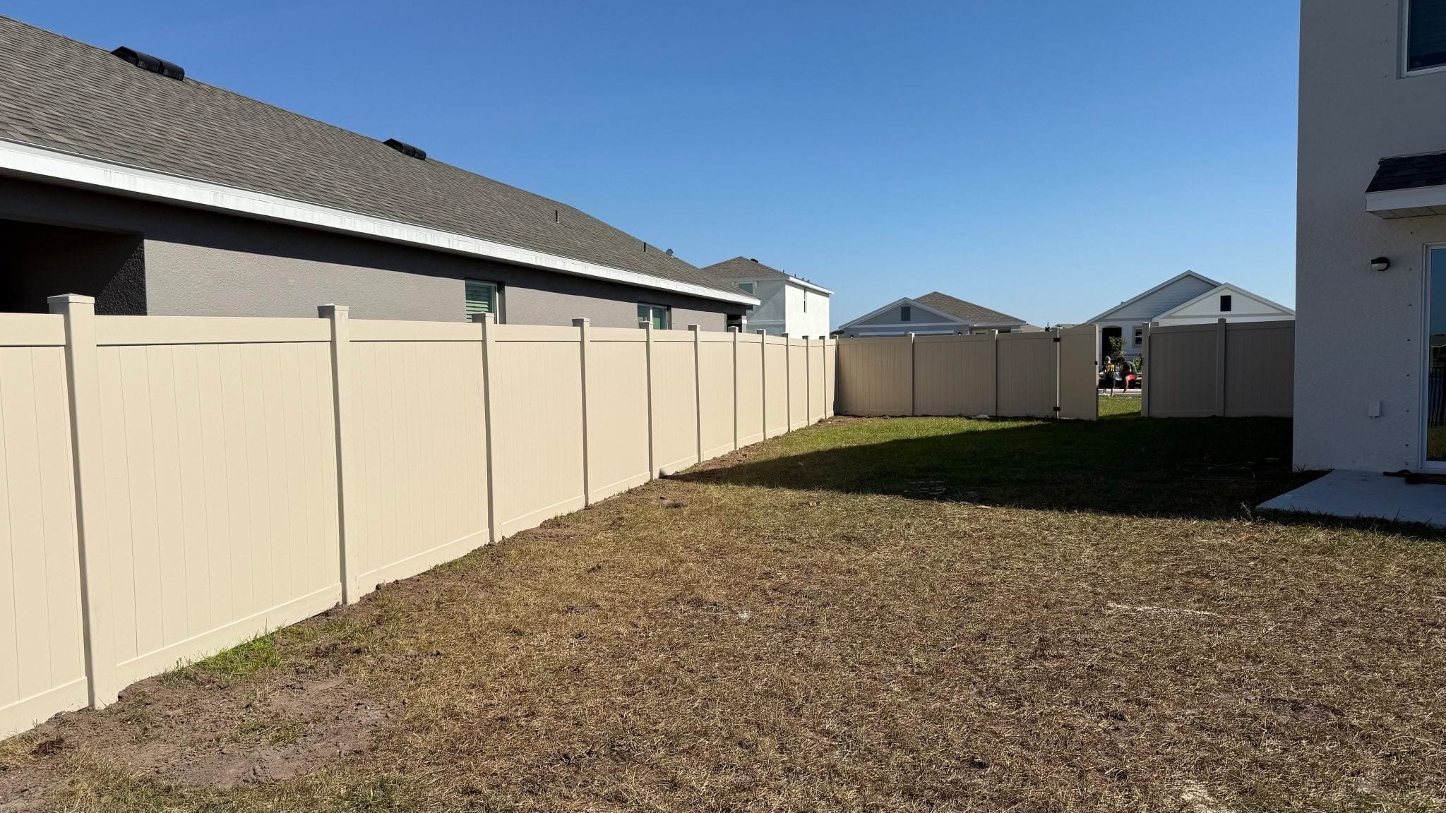 Tan vinyl privacy fence along a Florida home built by Wilson's Fencing